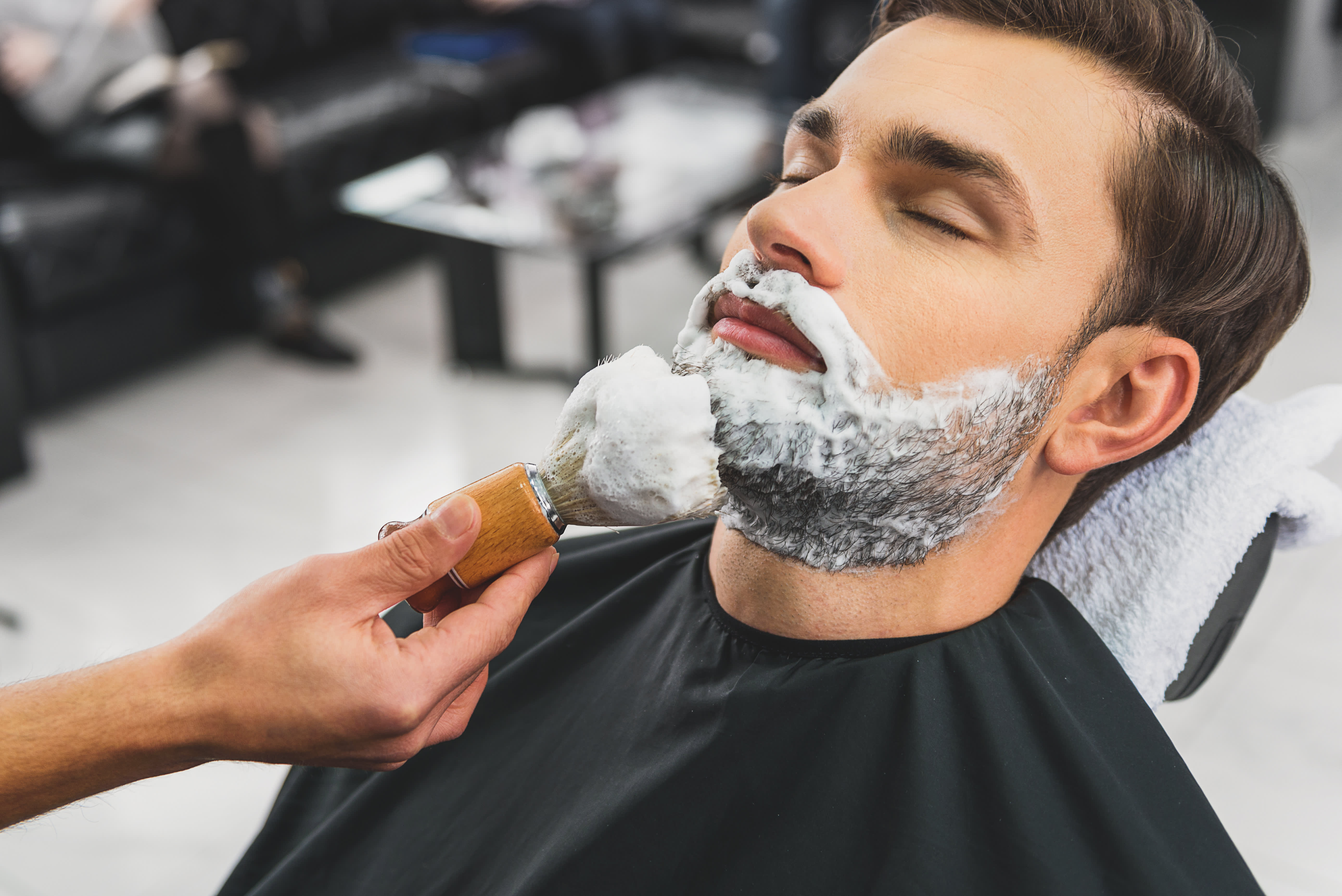 Мужчина бреет бороду. Бритье бороды. Помазок для бороды. Мужчина барбер бритье.
