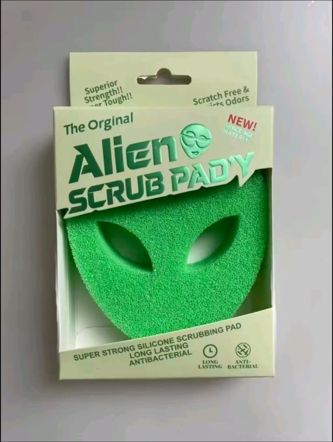 Green alien-shaped scrub pad in its retail packaging.